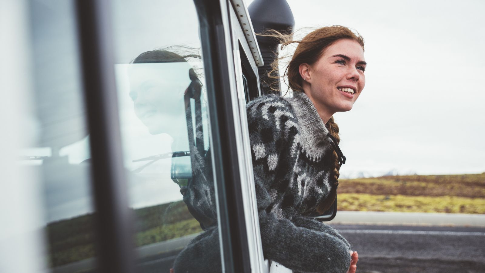 A woman looking out into the Icelandic landscape from a car window