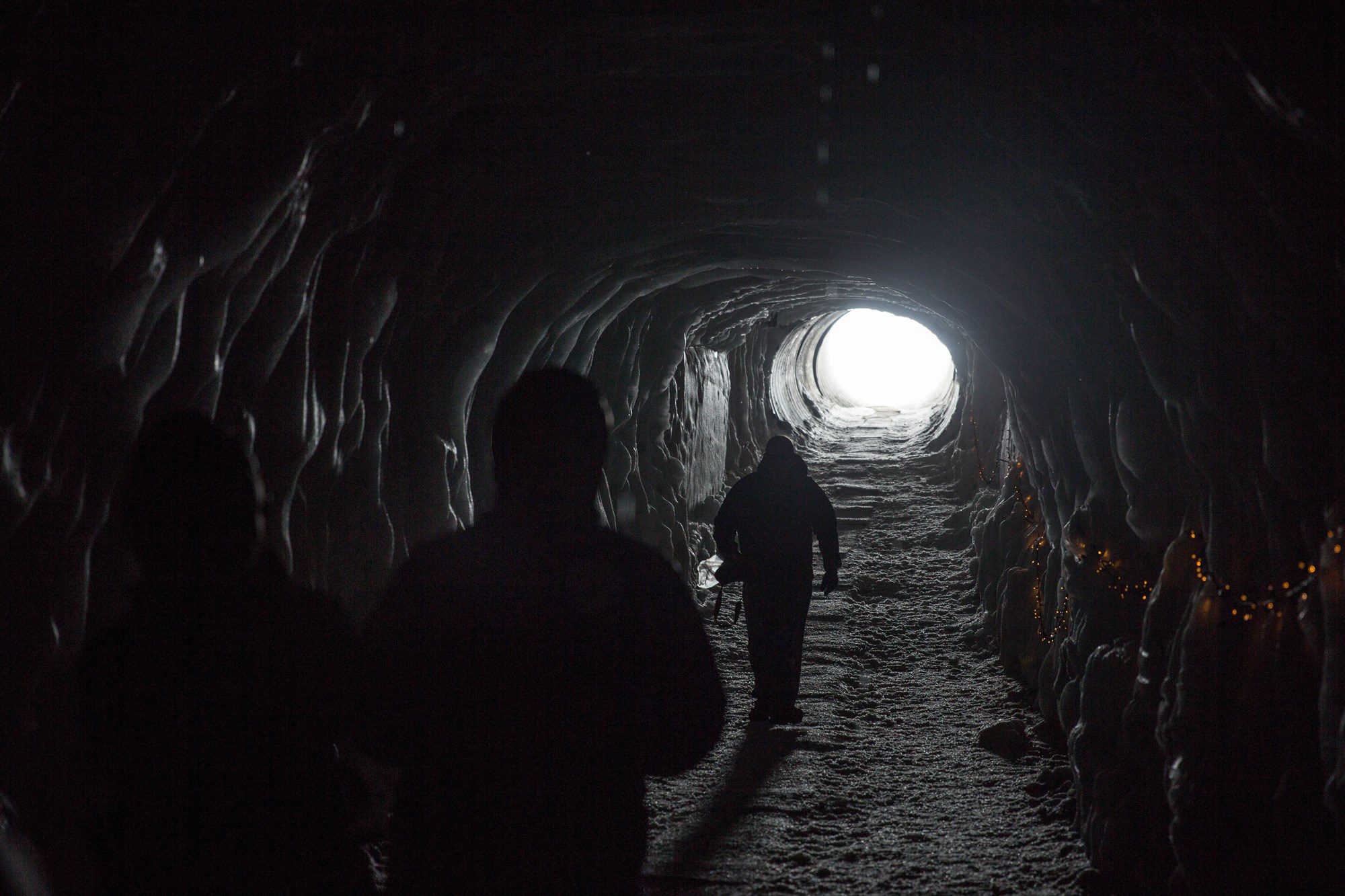  People walking through a dark tunnel towards the light in Iceland.