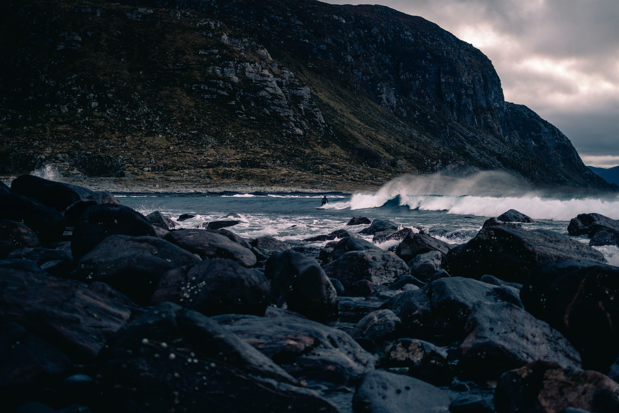 A surfer surrounded by the dramatic, dark volcanic rock in Iceland.