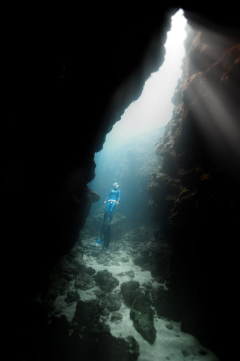 Scuba diver swimming out of an underwater cave.