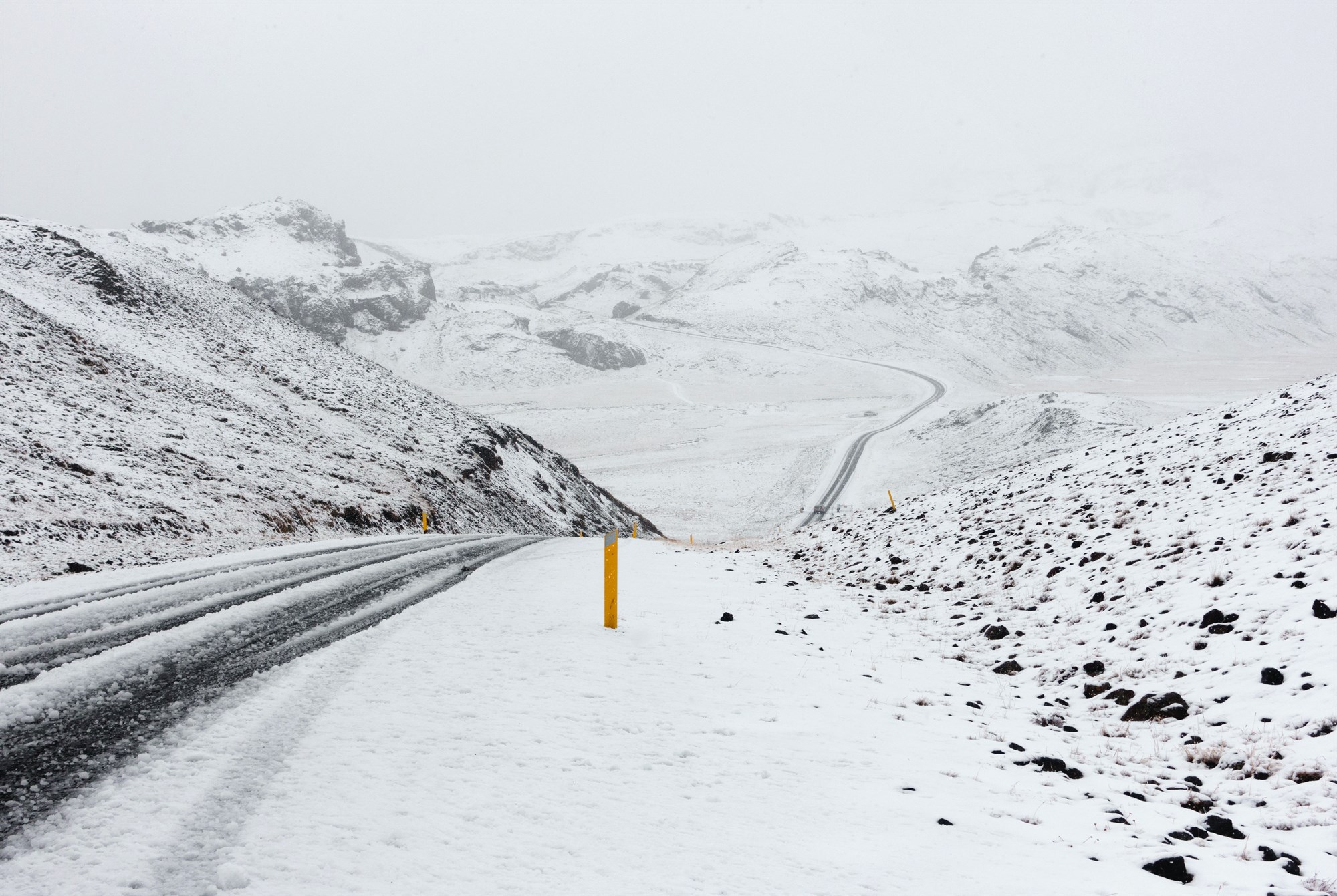 Snowy road over rolling Icelandic landscape.