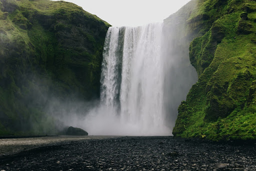 Huge waterfall in Iceland against green mossy cliffside