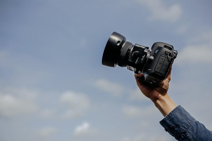 Hand holding a camera up in front of blue Iceland sky,