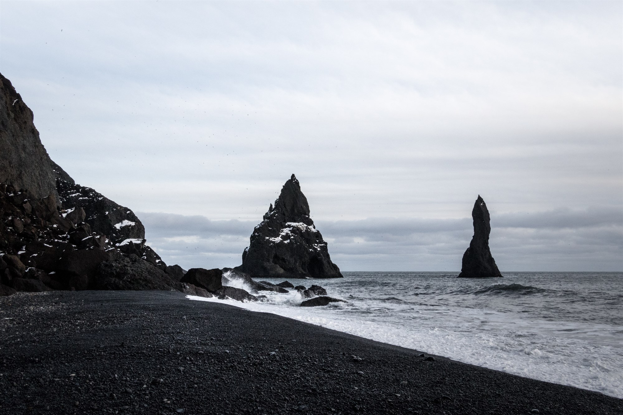 Dark rocks and black sand of Reynisfjara beach in Iceland.