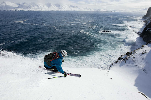 Person skiing in powdery snow next to the ocean.