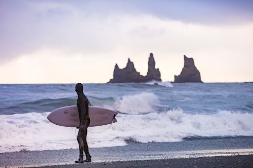 Surfer holding a board looking out to sea